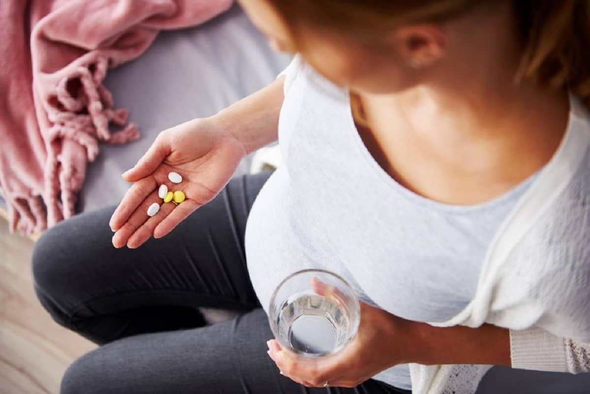 young pregnant woman taking supplements